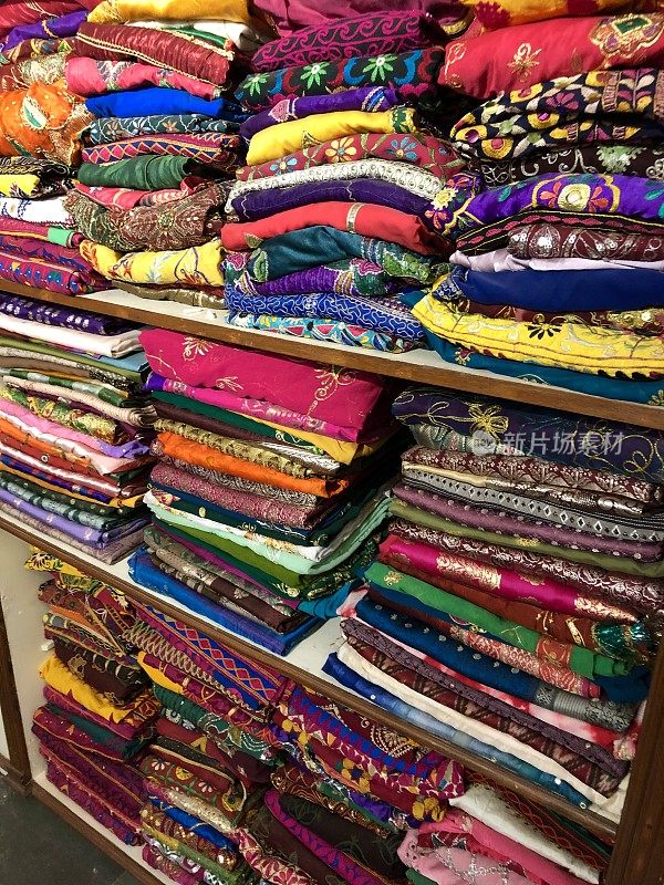 印度北方邦，Connaught Place，德里购物中心市场，彩色的印度织物材料堆放在货架上，丝巾，羊绒，床单和披肩